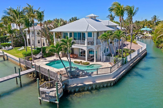 rear view of property with a swimming pool with hot tub, a water view, and a patio area