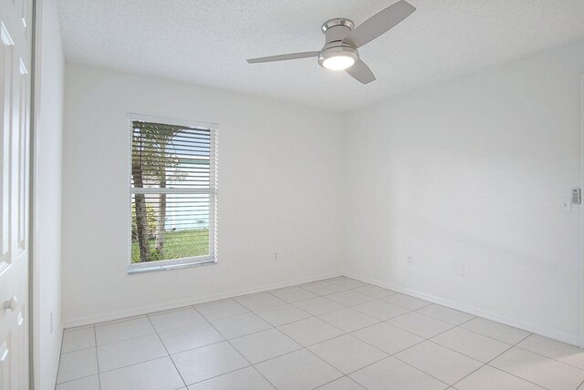 tiled empty room featuring ceiling fan