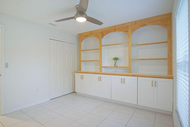 empty room with ceiling fan and light tile patterned flooring