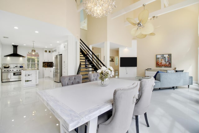 dining space with visible vents, stairs, recessed lighting, ceiling fan with notable chandelier, and a towering ceiling