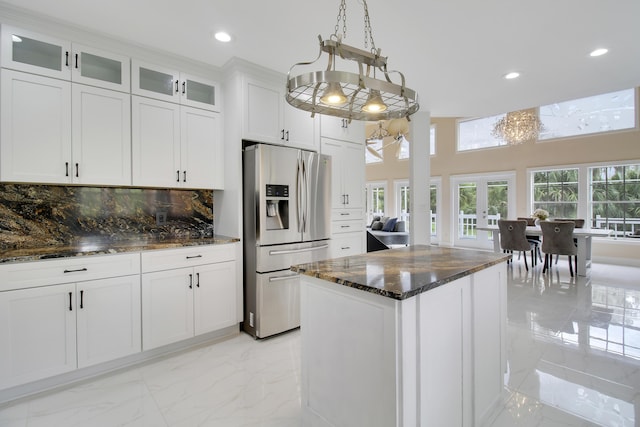 kitchen with backsplash, a kitchen island, stainless steel fridge with ice dispenser, white cabinetry, and hanging light fixtures