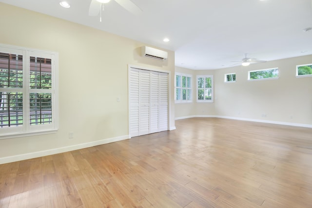 unfurnished room featuring a wall mounted air conditioner, ceiling fan, and light wood-type flooring