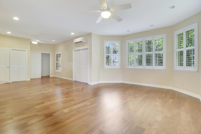 unfurnished room with light hardwood / wood-style flooring, a wall mounted AC, and ceiling fan