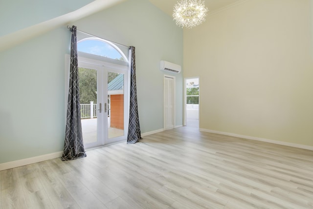 unfurnished room with a chandelier, french doors, a wall unit AC, and a healthy amount of sunlight