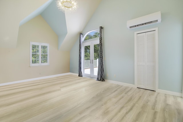 unfurnished bedroom with vaulted ceiling, wood finished floors, a chandelier, and a wall mounted AC