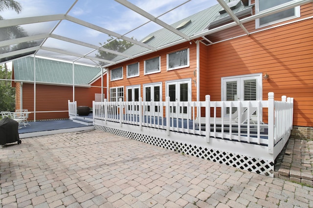 rear view of house featuring glass enclosure, a patio area, and a wooden deck