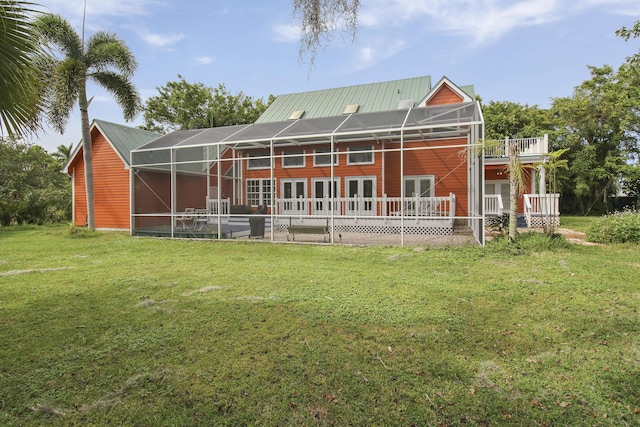 rear view of property featuring a lanai, metal roof, and a yard