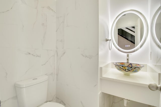 bathroom featuring vanity, toilet, and tile walls