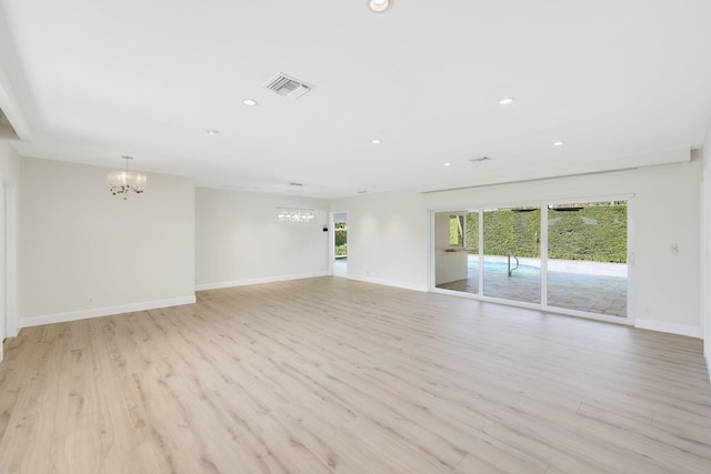 spare room with light hardwood / wood-style floors and a chandelier