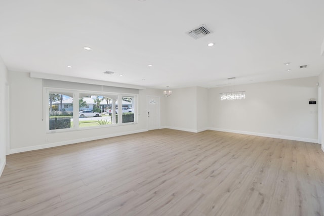 unfurnished living room with light hardwood / wood-style floors and a notable chandelier