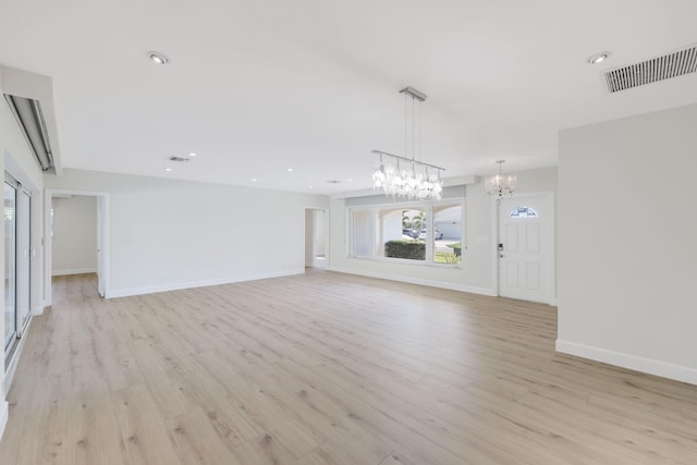 unfurnished living room featuring a notable chandelier and light hardwood / wood-style floors