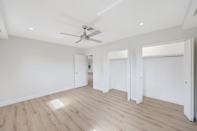 unfurnished bedroom featuring multiple closets, ceiling fan, and light hardwood / wood-style floors