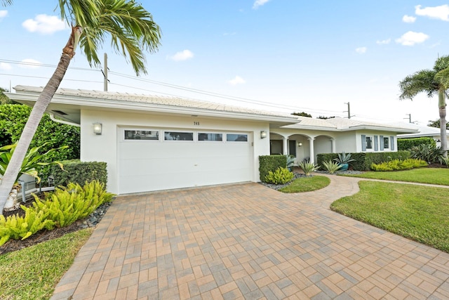 ranch-style house featuring a garage and a front lawn