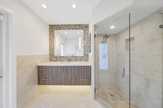 bathroom with tile patterned flooring, vanity, a shower with shower door, and tile walls