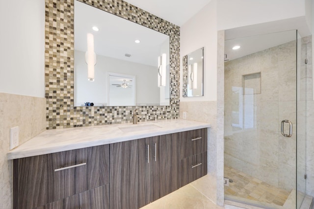 bathroom with ceiling fan, a shower with shower door, tile walls, and vanity