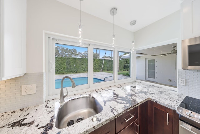 kitchen with sink, pendant lighting, dark brown cabinets, white cabinets, and range