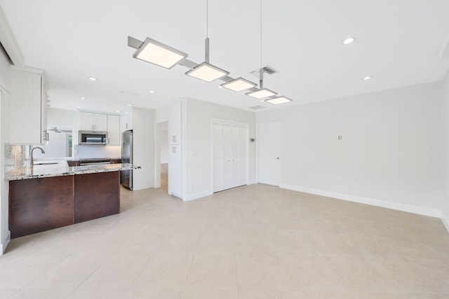 interior space featuring light stone countertops, white cabinetry, sink, stainless steel appliances, and backsplash