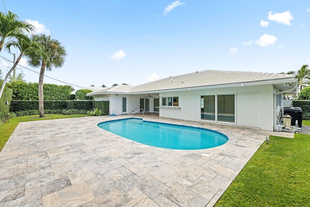 view of swimming pool with ceiling fan, a patio area, and a lawn