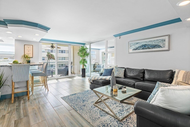 living room with ceiling fan, ornamental molding, and a wall of windows