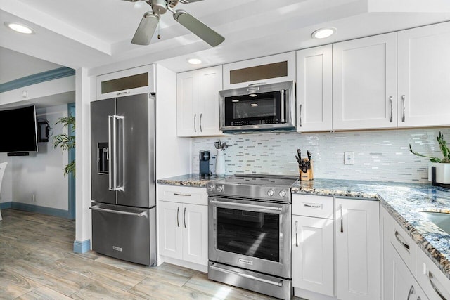 kitchen with appliances with stainless steel finishes, tasteful backsplash, white cabinetry, and light stone counters