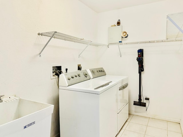 laundry room with light tile patterned flooring, washing machine and dryer, and sink