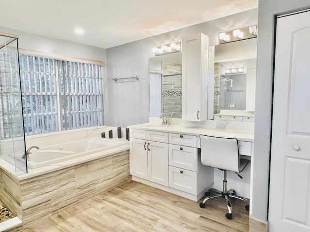 bathroom with hardwood / wood-style flooring, vanity, and plus walk in shower