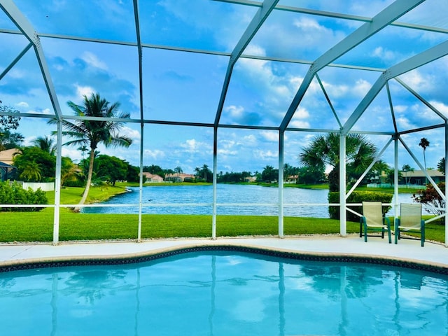 view of swimming pool featuring a lawn, glass enclosure, a patio area, and a water view