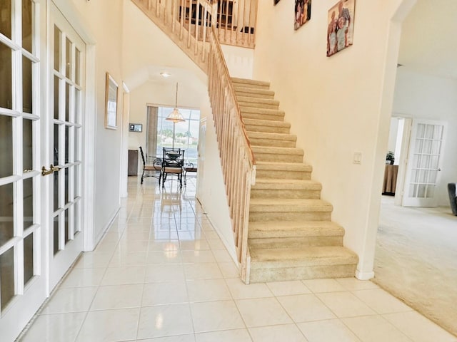 staircase featuring french doors, carpet floors, and a high ceiling