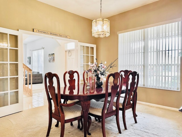 carpeted dining area with french doors and an inviting chandelier