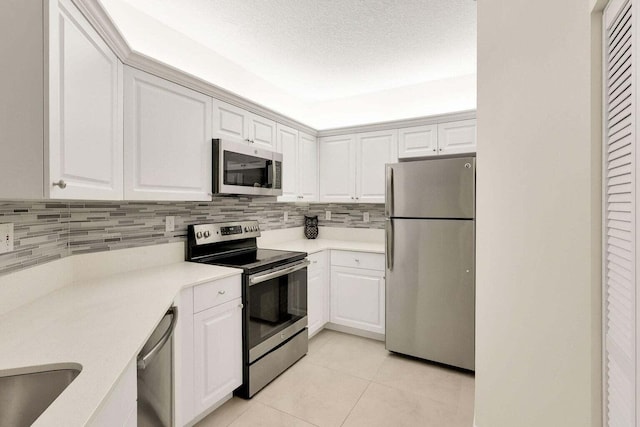 kitchen with white cabinets, light tile patterned floors, backsplash, and stainless steel appliances