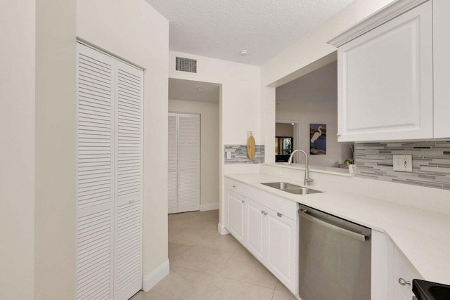 kitchen with dishwasher, white cabinetry, sink, and light tile patterned floors