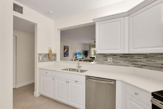 kitchen featuring backsplash, white cabinets, sink, stainless steel dishwasher, and light tile patterned floors