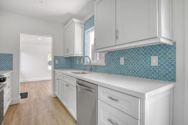 kitchen featuring dishwasher, backsplash, white cabinets, sink, and light hardwood / wood-style floors