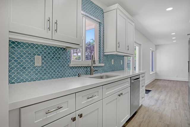 kitchen with dishwasher, sink, light hardwood / wood-style flooring, tasteful backsplash, and white cabinetry