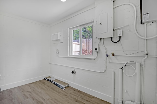 laundry room with light hardwood / wood-style floors, crown molding, and electric panel