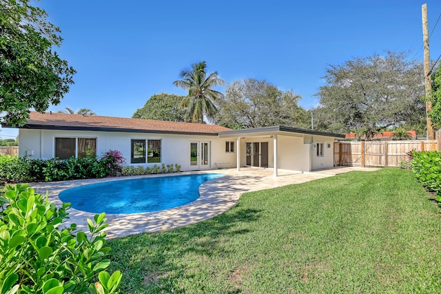 back of house featuring a patio, a fenced in pool, and a lawn