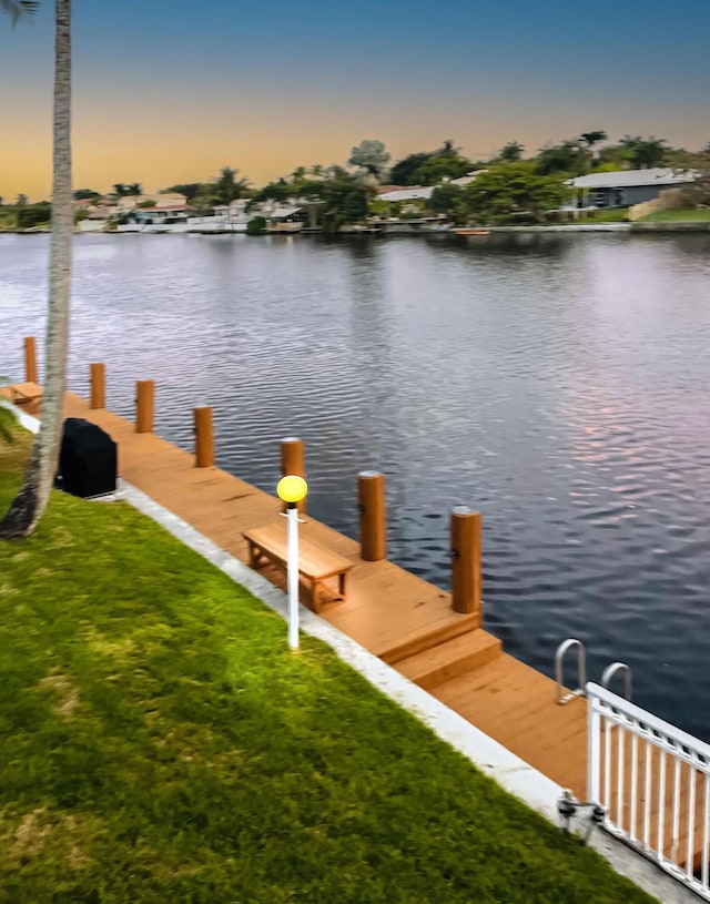 view of dock featuring a lawn and a water view