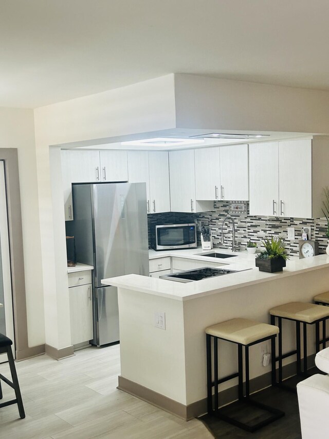 kitchen with pendant lighting, white cabinets, sink, appliances with stainless steel finishes, and tasteful backsplash