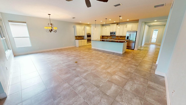 kitchen featuring stainless steel appliances, backsplash, an island with sink, pendant lighting, and white cabinets