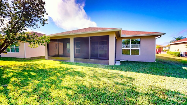 back of property featuring a lawn and a sunroom