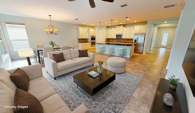 tiled living room featuring ceiling fan with notable chandelier and sink