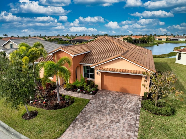 mediterranean / spanish-style home featuring a front yard, a water view, and a garage