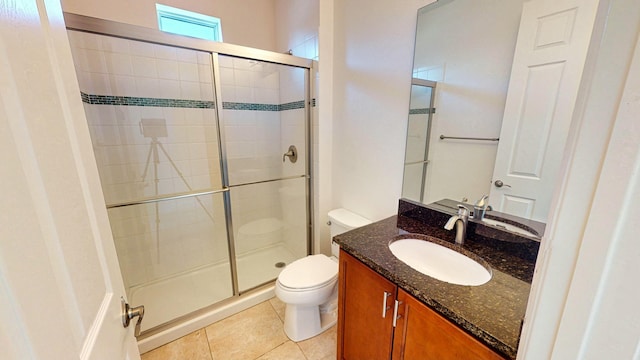 bathroom with tile patterned floors, vanity, a shower with shower door, and toilet