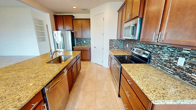 kitchen featuring appliances with stainless steel finishes, light stone counters, sink, light tile patterned floors, and an island with sink