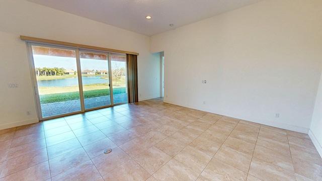 tiled spare room featuring a water view