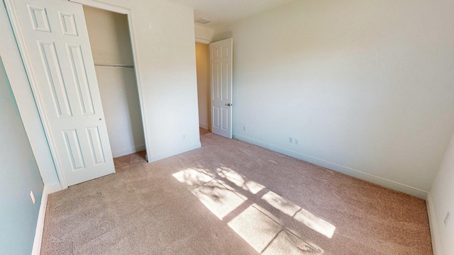 unfurnished bedroom with a closet and light colored carpet