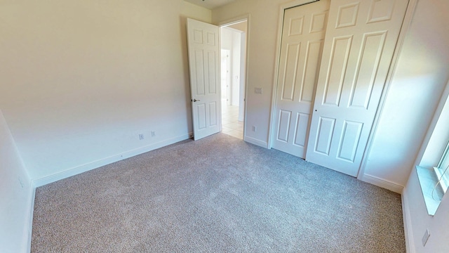 unfurnished bedroom featuring light colored carpet and a closet