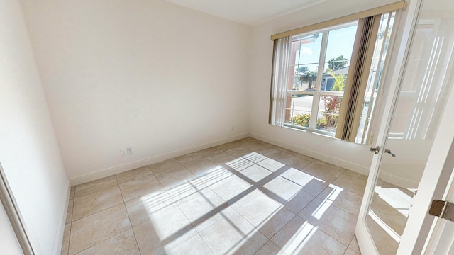 tiled spare room with a healthy amount of sunlight and french doors