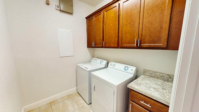 clothes washing area with separate washer and dryer, light tile patterned floors, and cabinets