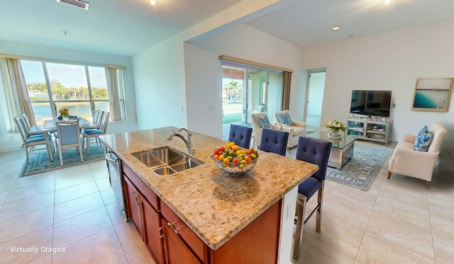 kitchen with light stone countertops, a kitchen island with sink, sink, light tile patterned floors, and dishwasher